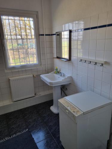a white bathroom with a sink and a window at FEWO NEUBEEREN in Großbeeren