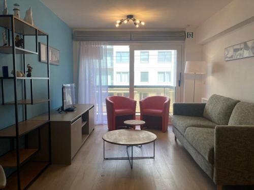 a living room with a couch and a table and chairs at Oostduinkerke Apartments in Oostduinkerke