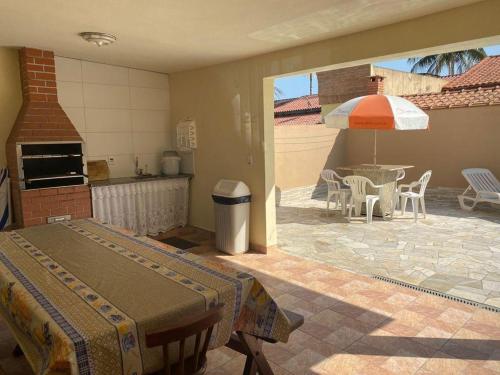 een kamer met een keuken en een tafel met een paraplu bij Beachouse Marissol Morada da Praia in Bertioga