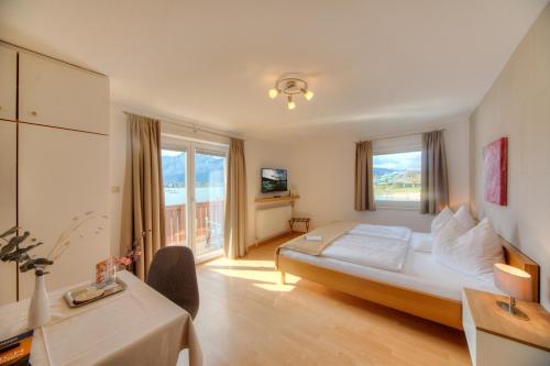 a hotel room with a bed and a desk and window at Seepension Hemetsberger in Mondsee