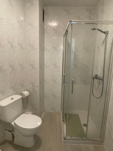 a bathroom with a toilet and a glass shower at Precioso Apartamento en Puertollano in Puertollano