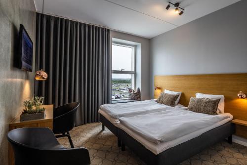 a hotel room with a bed and a desk and a window at Aalborg Airport Hotel in Aalborg