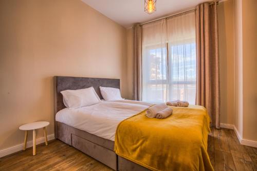 a bedroom with a bed with a yellow blanket and a window at Cozy 2BD Apartment in Bansko in Bansko