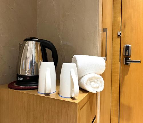a coffee pot and towels on a shelf at Morvee Hotels Alipore Kolkata in Kolkata