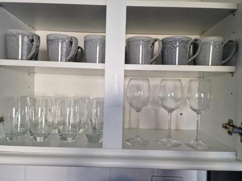 une rangée de verres à vin dans une étagère avec des tasses dans l'établissement 4 beds with links to motorways, à Leeds
