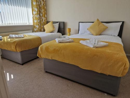 um quarto com 2 camas com lençóis e saias amarelas em 4 beds with links to motorways em Leeds