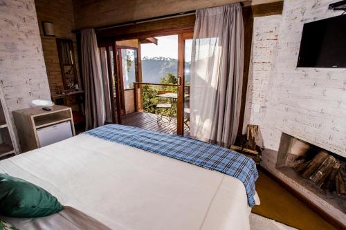 1 dormitorio con 1 cama frente a una chimenea en Pousada Villa Catarina, en Gonçalves