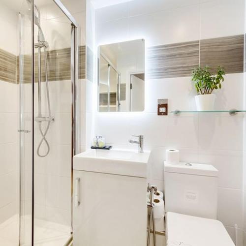 a white bathroom with a sink and a shower at Nell Gwynn Chelsea Accommodation in London