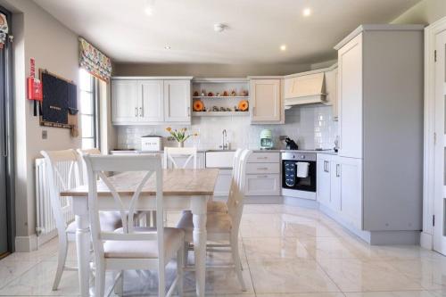 a kitchen with white cabinets and a table and chairs at Escape Ordinary at Lough Erne Golf Village No.52 in Enniskillen