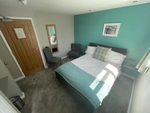 a bedroom with a bed with a blue wall at Pen Mar Guest House in Tenby