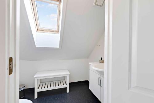 ein Bad mit einem weißen Waschbecken und einem Fenster in der Unterkunft Charming Architect-designed Terraced House With Sea View in Bro