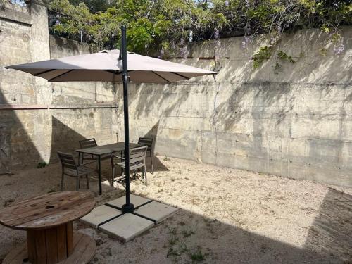 une table avec un parasol à côté d'une table et de chaises dans l'établissement La Glycine - Parking gratuit - AC CLIM - Cour privé -, à Villeneuve-lès-Avignon