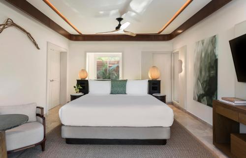 a bedroom with a white bed and a tv at Fairmont Mayakoba in Playa del Carmen