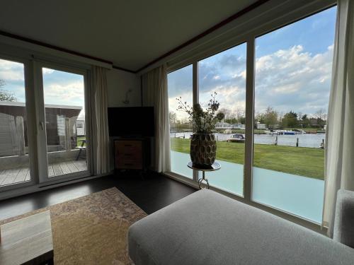 een woonkamer met grote ramen en een vaas op een tafel bij Chalet Havenzicht Eernewoude in Earnewâld
