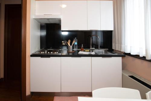 a kitchen with white cabinets and a sink at Residence La Fenice in Padova