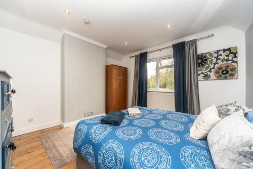a bedroom with a blue bed and a window at 6 bedrooms beautiful home 3 bathrooms, quiet location with garden near Legoland Windsor Heathrow in Maidenhead
