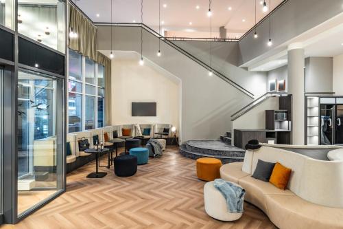 a lobby with a couch and chairs and tables at ibis Styles Bielefeld City in Bielefeld