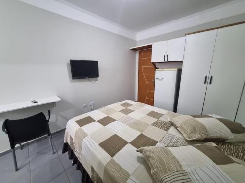 a bedroom with a bed and a desk and a television at Studio GT in São Carlos