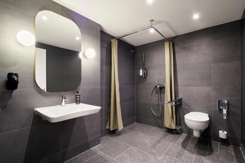 a bathroom with a sink and a toilet and a mirror at ibis Styles Bielefeld City in Bielefeld