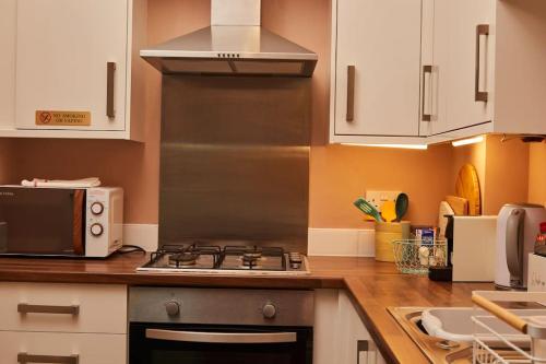 a kitchen with a stove and a microwave at Lovely Chique Newcastle Abode - Sleeps 4 - First floor in Elswick