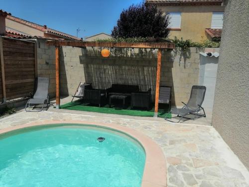 - une piscine dans une cour avec 2 chaises et une cheminée dans l'établissement Inadad, à Saint-Étienne-du-Grès