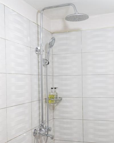 a shower in a bathroom with white tiles at Andrella Home Arusha in Arusha