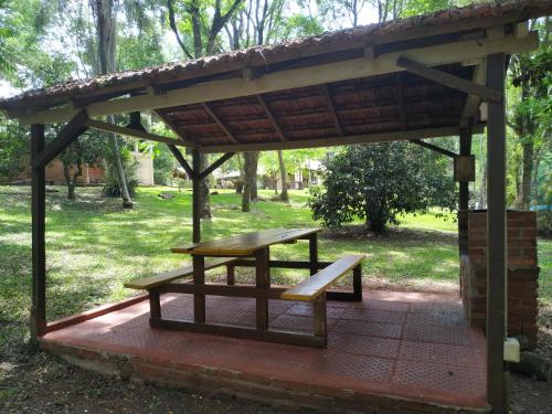 a picnic table and bench under a pavilion in a park at Complejo Paranay in Puerto Paranay