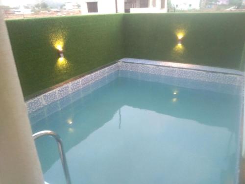 een zwembad met twee lichten in een groene kamer bij WHITE SMOKE villa in Igatpuri
