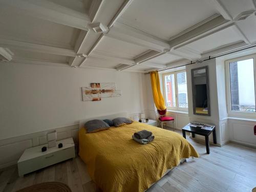 - une chambre avec un lit et une couverture jaune dans l'établissement Au clair de la Lune - jusqu'à 4 personnes, centre historique, à Porrentruy