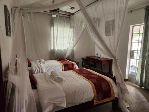 a bedroom with two beds with mosquito nets at Jacaranda Lodge in Victoria Falls