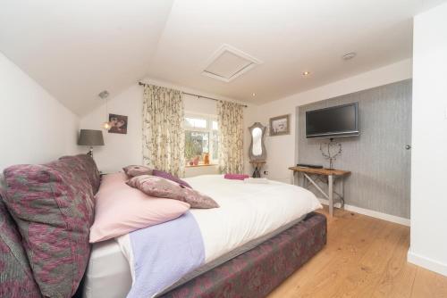 a bedroom with a bed with a couch and a tv at 6 bedrooms beautiful home 3 bathrooms, quiet location with garden near Legoland Windsor Heathrow in Maidenhead