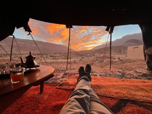 a person sitting in a tent looking out at the desert at Auberge Palacio Sidi Hamza in Tazrouft