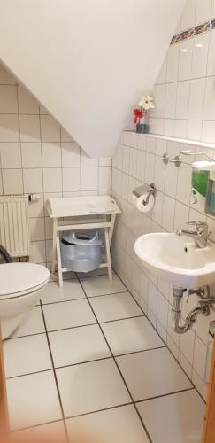 ein weiß gefliestes Bad mit 2 Waschbecken und einem WC in der Unterkunft Ferienhaus Knopf -direkt am Küstenwald in Zinnowitz