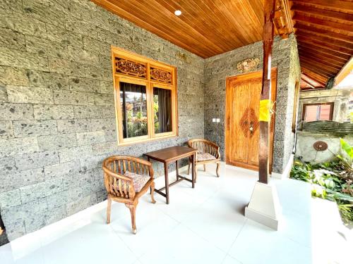 a patio with a table and chairs and a wooden ceiling at DIMUWA Ubud in Ubud