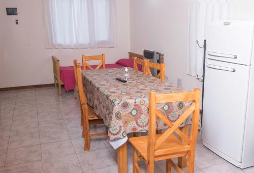 a dining room with a table and chairs and a refrigerator at Apartamentos Matices in El Calafate