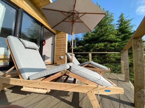 a lounge chair with an umbrella on a deck at Valley View Pendle in Foulridge