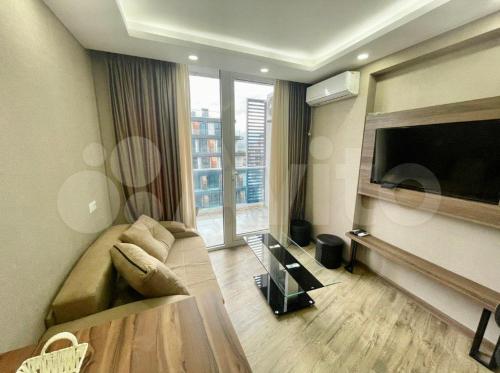 a living room with a couch and a flat screen tv at GOOD-VIBES Apartments in Batumi