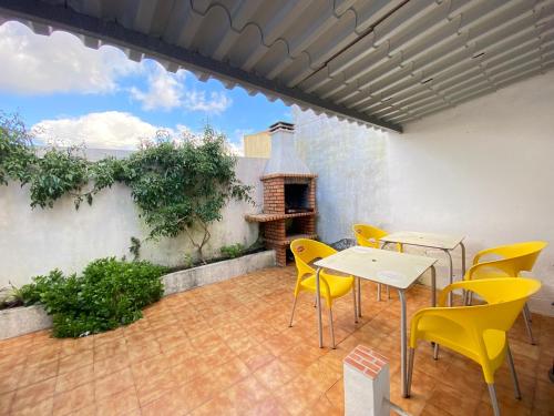 eine Terrasse mit gelben Stühlen und einem Tisch und einem Kamin in der Unterkunft Casa Alto Do Viso in Figueira da Foz