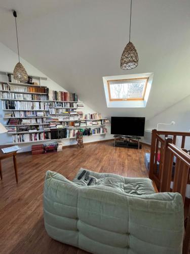 a living room with a couch and a tv and books at Gazonfier in Le Mans