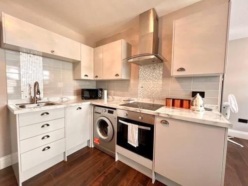 a kitchen with white cabinets and a washing machine at Lovely Studio close to Brighton Station in Brighton & Hove