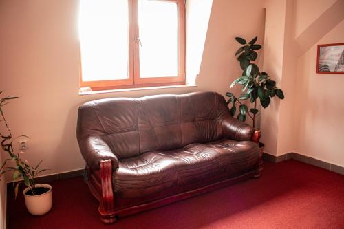 a brown leather couch in a room with a window at Penzión Tavel in Prešov