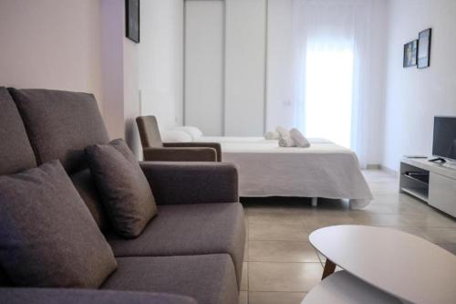 a living room with a couch and a bed at Sal Mar Suites in Santa Eularia des Riu
