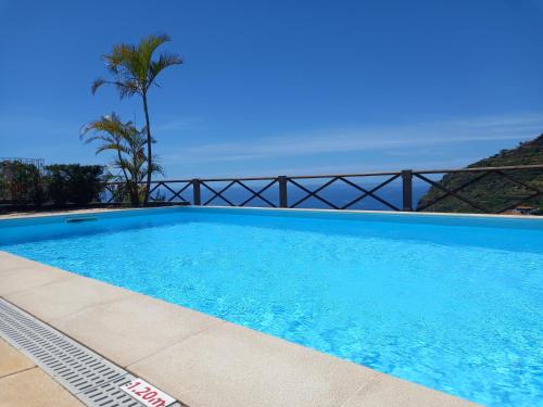a blue swimming pool with a view of the ocean at Tropical Garden in Arco da Calheta