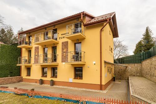 a yellow house with balconies and a wall at Penzión Zunama in Bardejovské Kúpele