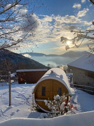 a wooden cabin in the snow with the sun behind it at 2 CUORI E UN B&B in Sueglio
