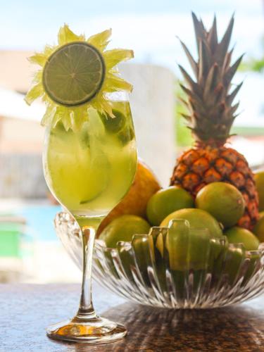 a bowl of fruit with a drink in a wine glass at Estação do Sol Praia Hotel in Porto De Galinhas