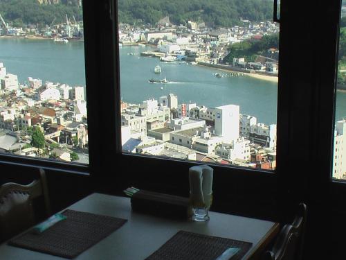 a table with a view of a city from a window at Onomichi View Hotel Seizan in Onomichi