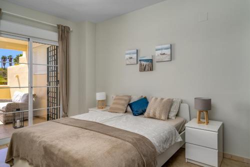 een witte slaapkamer met een bed en een balkon bij Bil bil golf apartment in Benalmádena