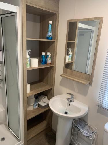 a bathroom with a sink and a mirror at The Palm - Large Static Caravan near Margate, Kent in Birchington