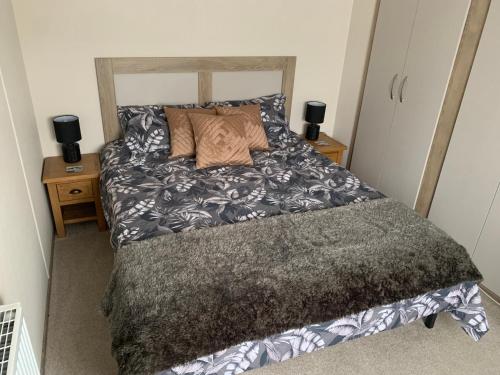 a bed in a small room with two night stands at The Palm - Large Static Caravan near Margate, Kent in Birchington